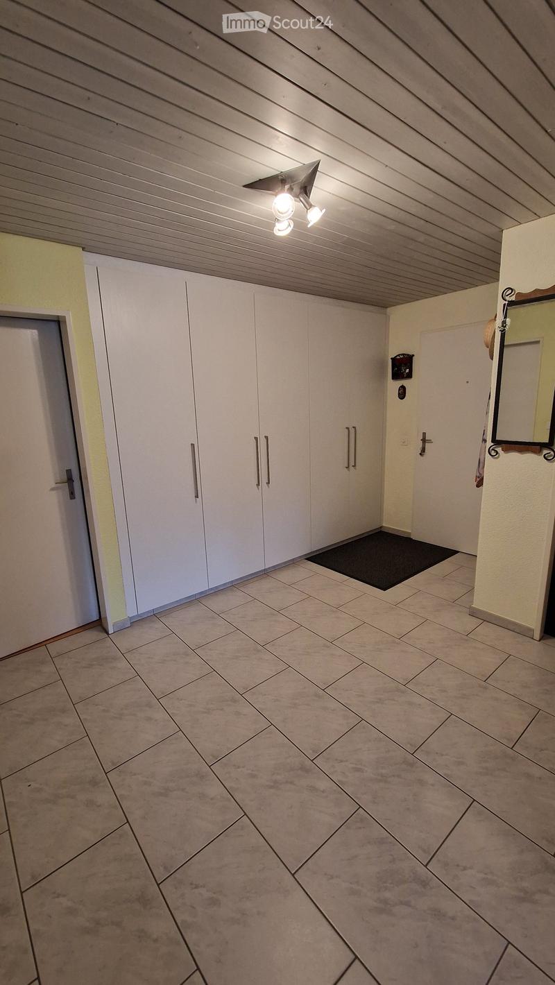 Empty hallway with tiled floor, white closet doors, and a small black doormat near the entrance.