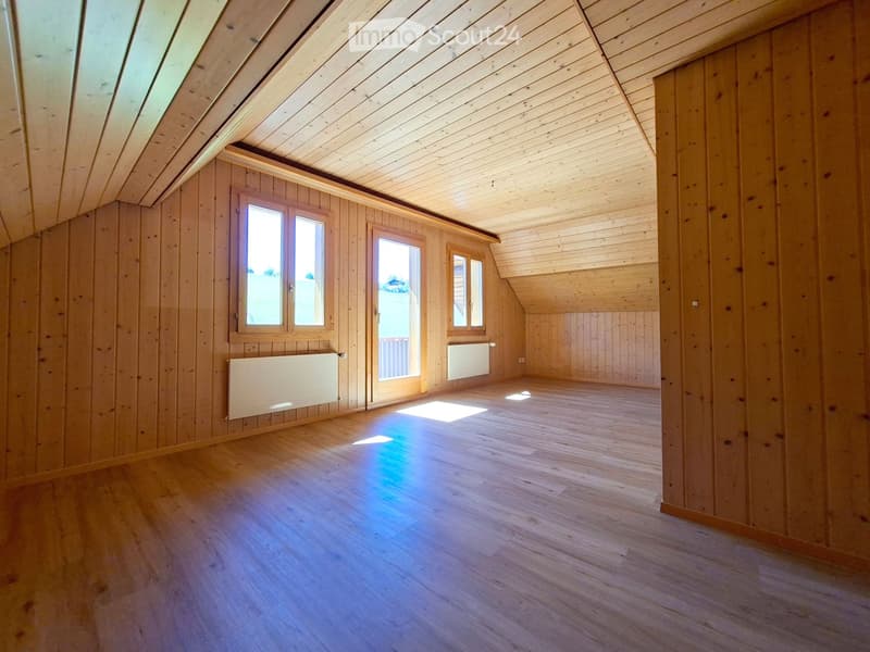 Empty attic room with wooden walls, wooden floor, and skylight windows. No furniture or equipment present.
