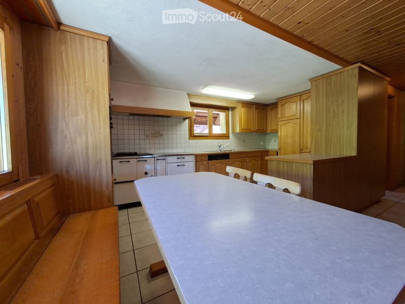 Bright kitchen with wooden cabinets, a central island, and a dining table with chairs. The space features a stove, sink, and ample storage.