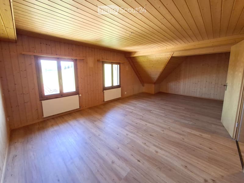 Empty attic room with wooden walls, wooden floor, and skylight windows. No furniture or equipment present.