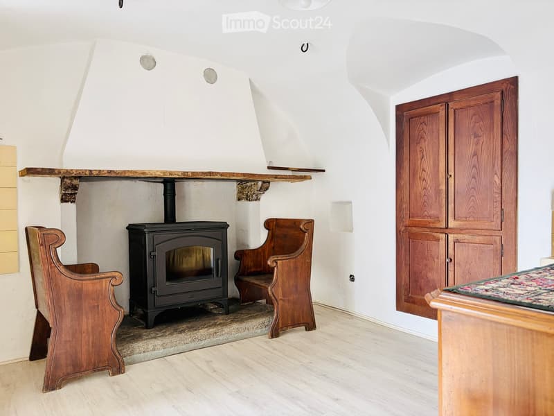 Cozy room with a wood-burning stove, wooden chairs, a bench, and a wooden cabinet.