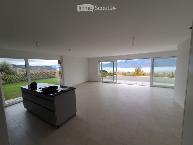Bright, open room with large windows and sliding doors leading to a balcony, featuring a modern desk and chair.
