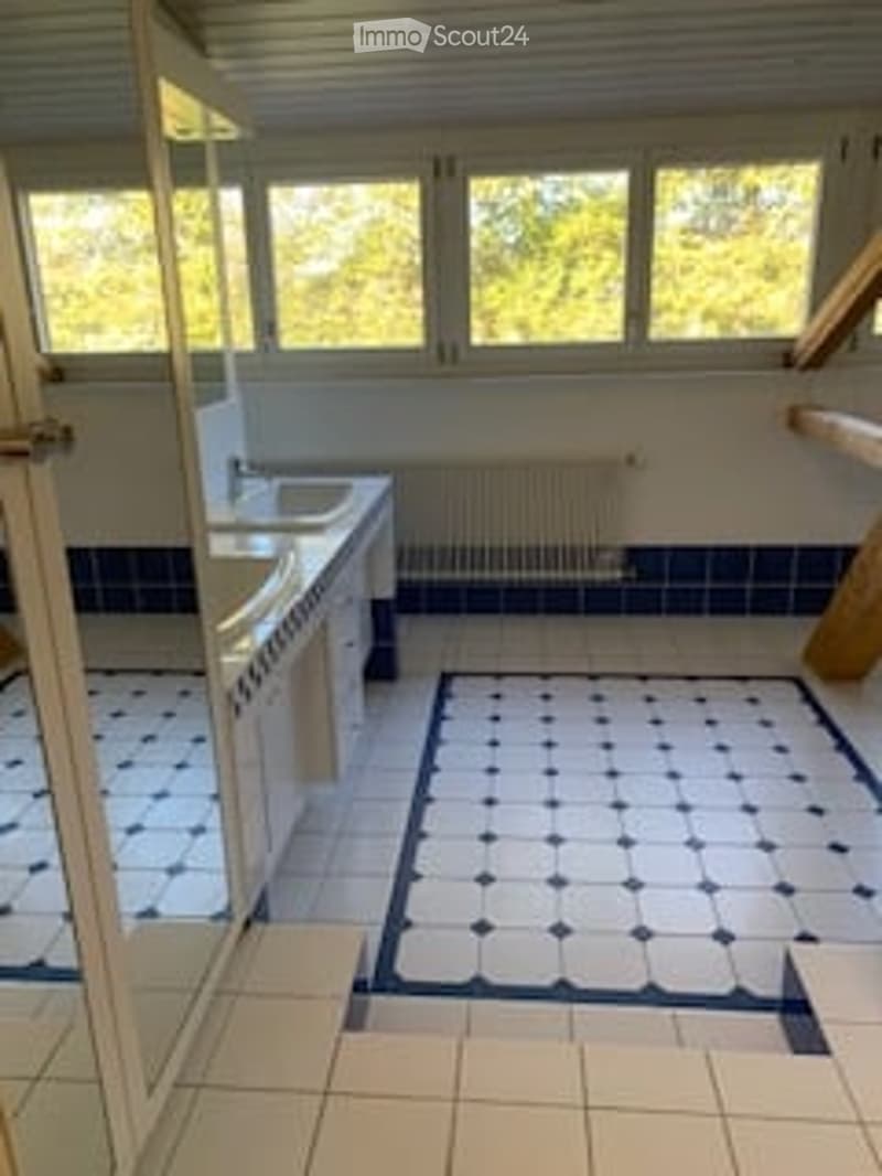 Modern kitchen with white tiled walls, blue and white checkered floor, stainless steel sink, stove, and radiator.