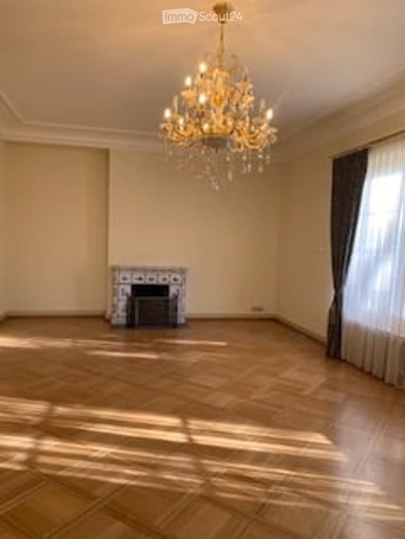 Empty room with wooden flooring, large windows, and a fireplace. No furniture or equipment present.