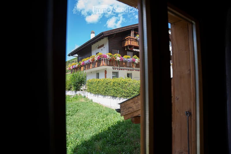 2 story house, wooden exterior, balcony with flowers, white walls, green lawn