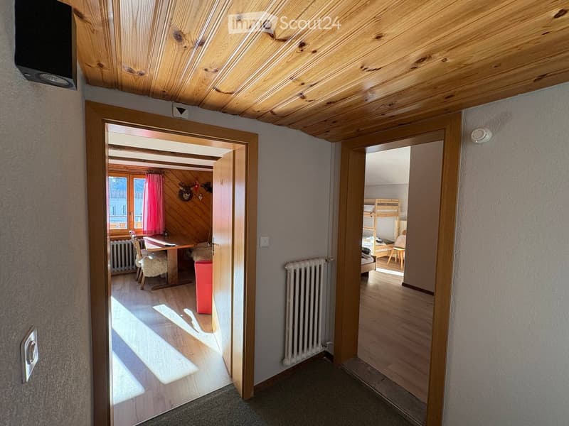 wooden ceiling, wooden floor, radiator, wooden doors, wooden table, chairs, red curtain, deer head on wall, bunk bed