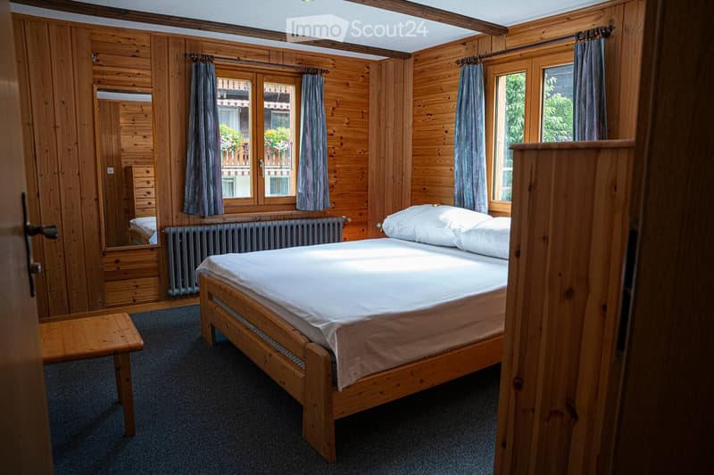 wooden walls, bed, radiator, window with curtains, wooden table, mirror