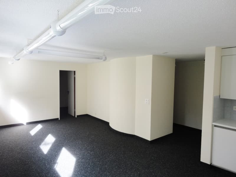 empty room with black floor, white walls, 2 lights on ceiling, small doorway, power outlet on wall, 1 white cabinet