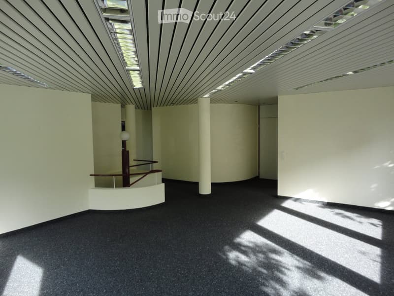 a room with white walls, black floor, central column, lamp, shadow on the floor
