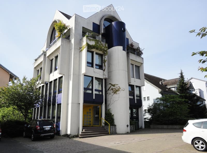 Modern building with 4 floors, white exterior, blue accents, yellow entrance, large windows, balconies, small garden in front