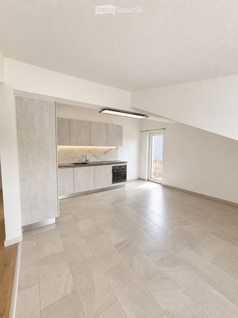 Modern kitchen with light-colored cabinets, a sink, stove, and oven. The space features tiled flooring and a sliding glass door leading to a balcony.