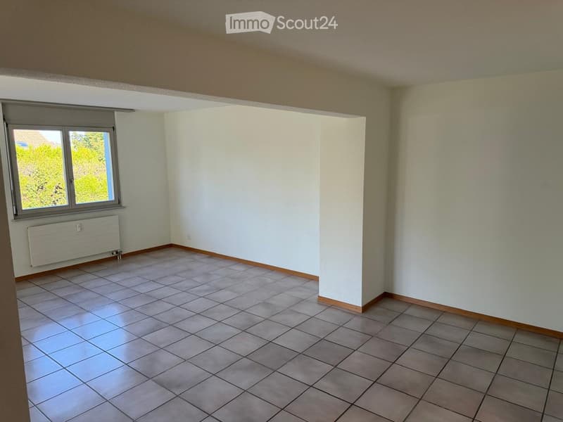 Empty room with tiled floor, white walls, and a window with a radiator below it.