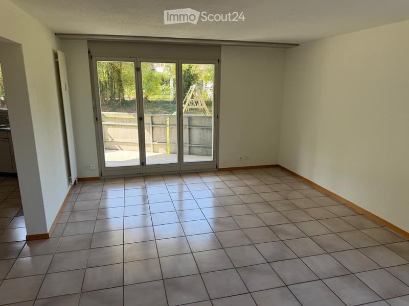Empty room with tiled floor, light-colored walls, and large sliding glass doors leading to an outdoor area.