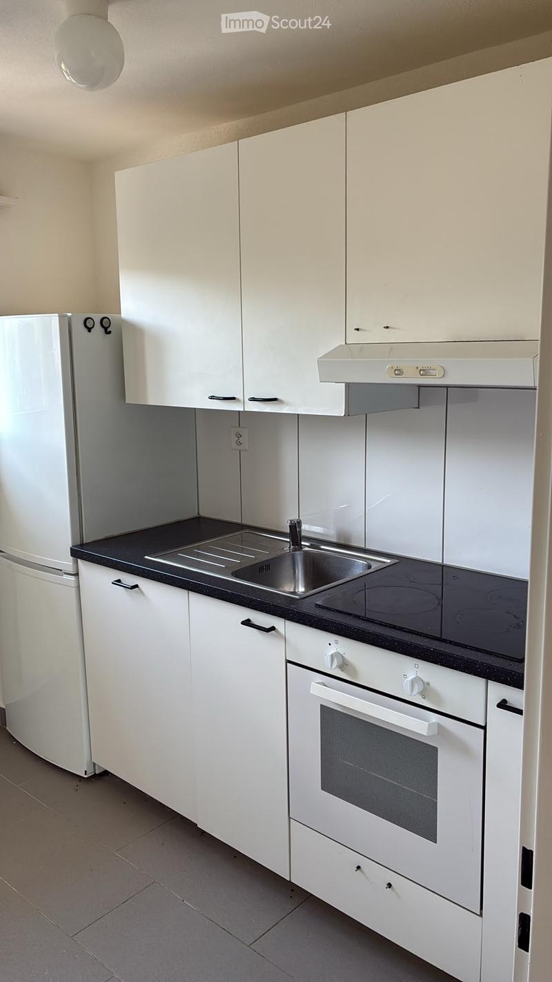 Modern kitchen with white cabinets, black countertop, stainless steel sink, induction cooktop, and built-in oven.