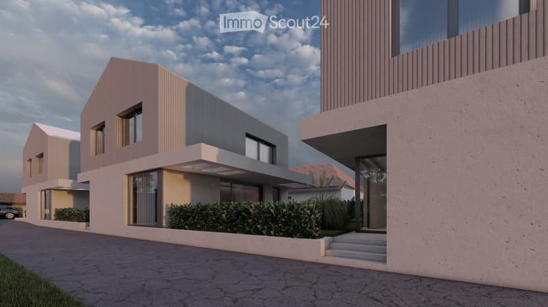 Two-story modern house with a flat roof, gray and beige exterior, large windows, and a garage. The house has a landscaped front yard with shrubs and plants.