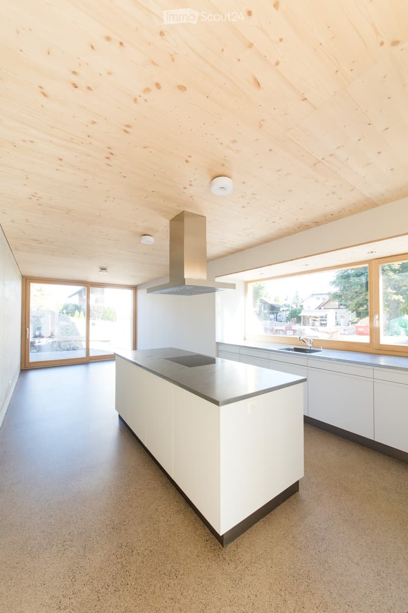 Modern kitchen with white cabinets, a central island, and large windows overlooking the outdoors.