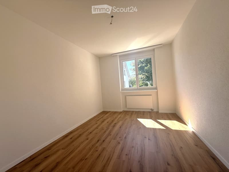 Empty room with wooden flooring, white walls, and a window with blinds. No furniture or equipment is present.