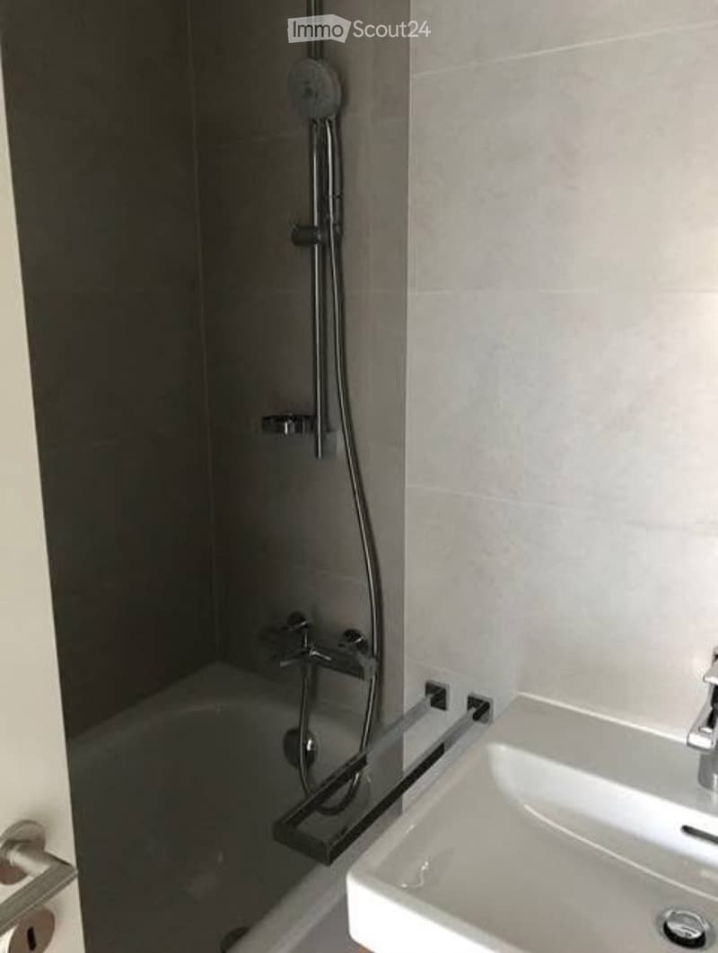 Modern bathroom with a bathtub, glass-enclosed shower, and a white sink with a chrome faucet.