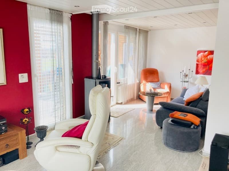 Modern living room with white leather sofa, orange armchair, coffee table, and decorative items.