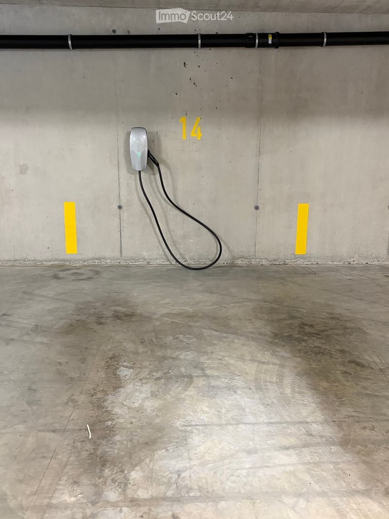 Empty concrete-walled room with a charging station attached to the wall and a cable extending to the floor.