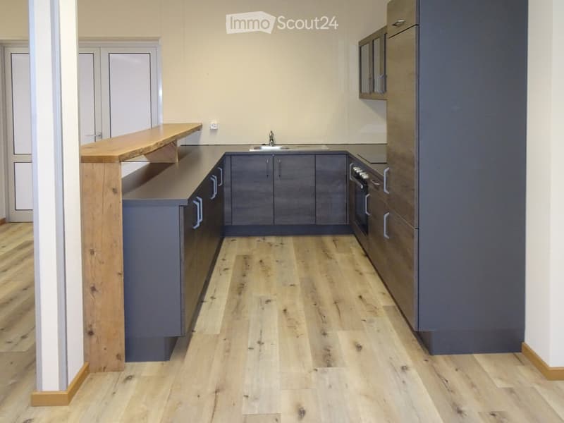 Modern kitchen with dark grey cabinets, a wooden island, and light wooden flooring.