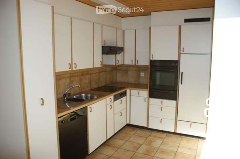 Bright kitchen with white cabinets, stainless steel appliances, and a tiled floor.