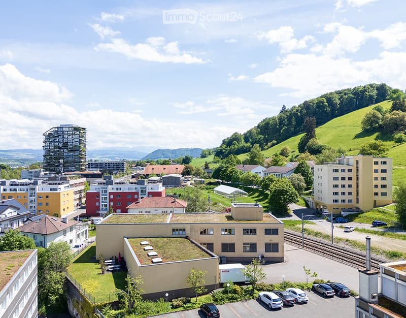 Aerial view of a mixed urban area with residential buildings, a parking lot, and green spaces.