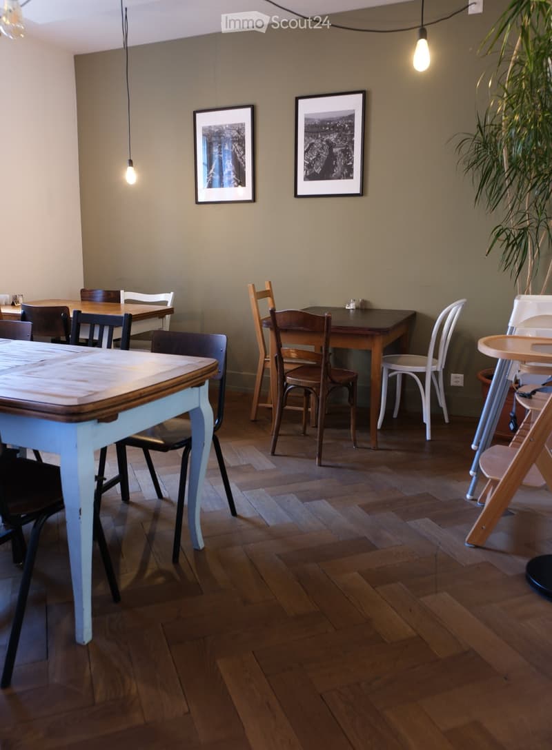 A cozy dining area with wooden tables, chairs, and a baby chair, complemented by framed artwork and a potted plant.