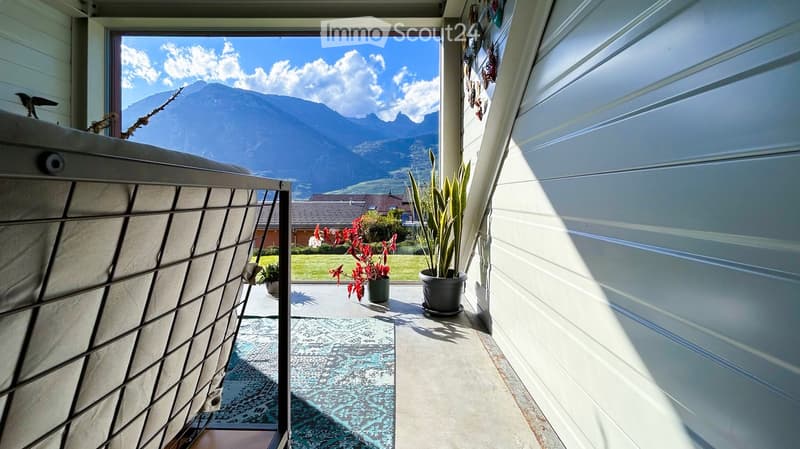 Balcony with a scenic mountain view, featuring a rug and potted plants.