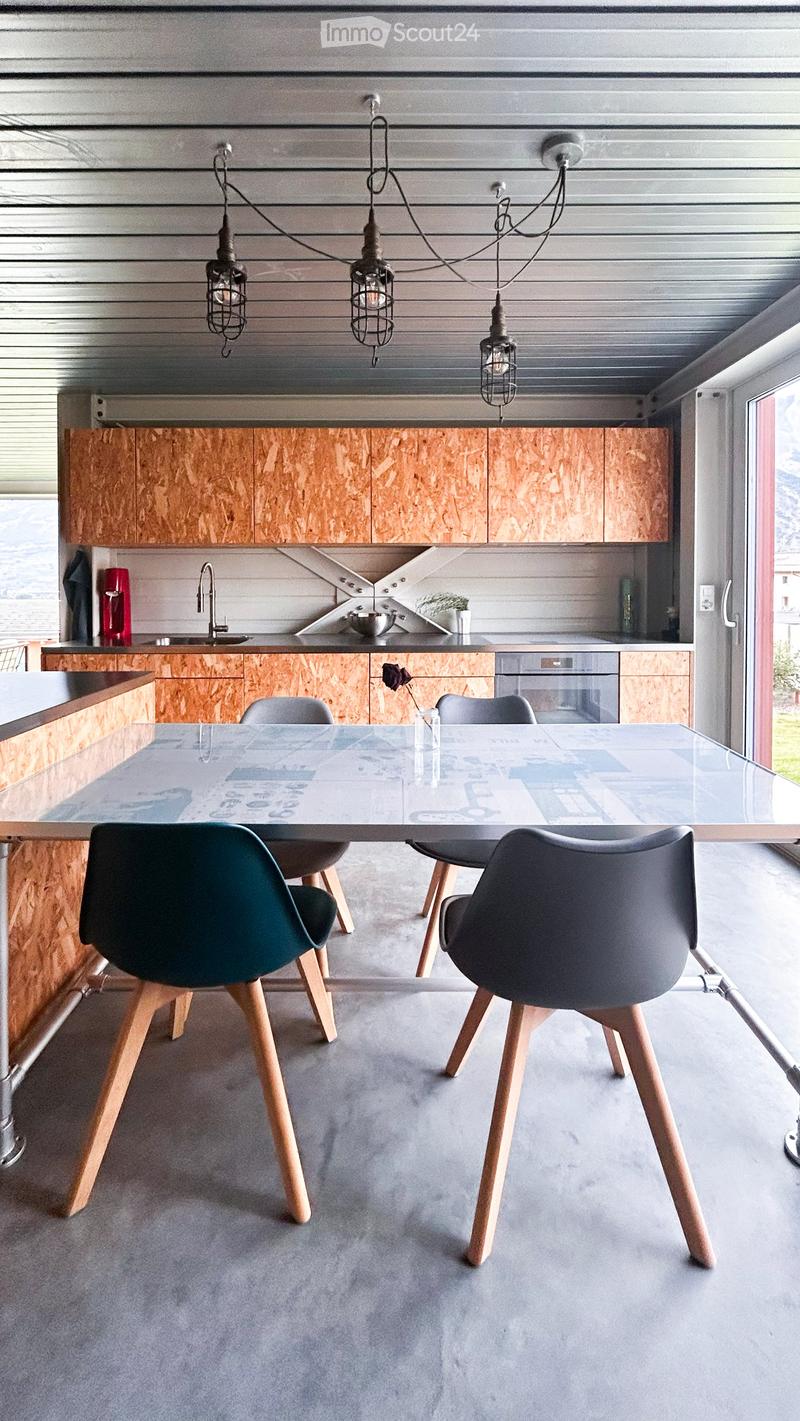 Modern kitchen with wooden cabinets, stainless steel appliances, a glass dining table, and four chairs.