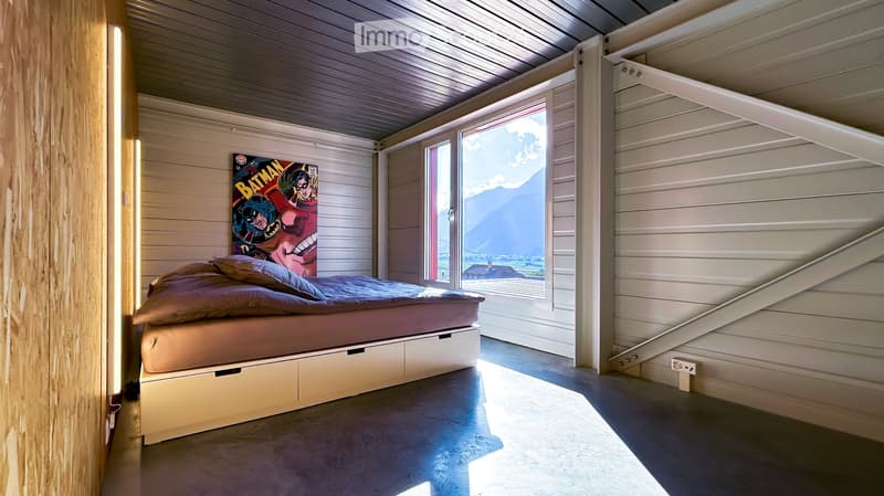 Modern bedroom with a built-in bed, storage drawers, and a large window offering a scenic mountain view.