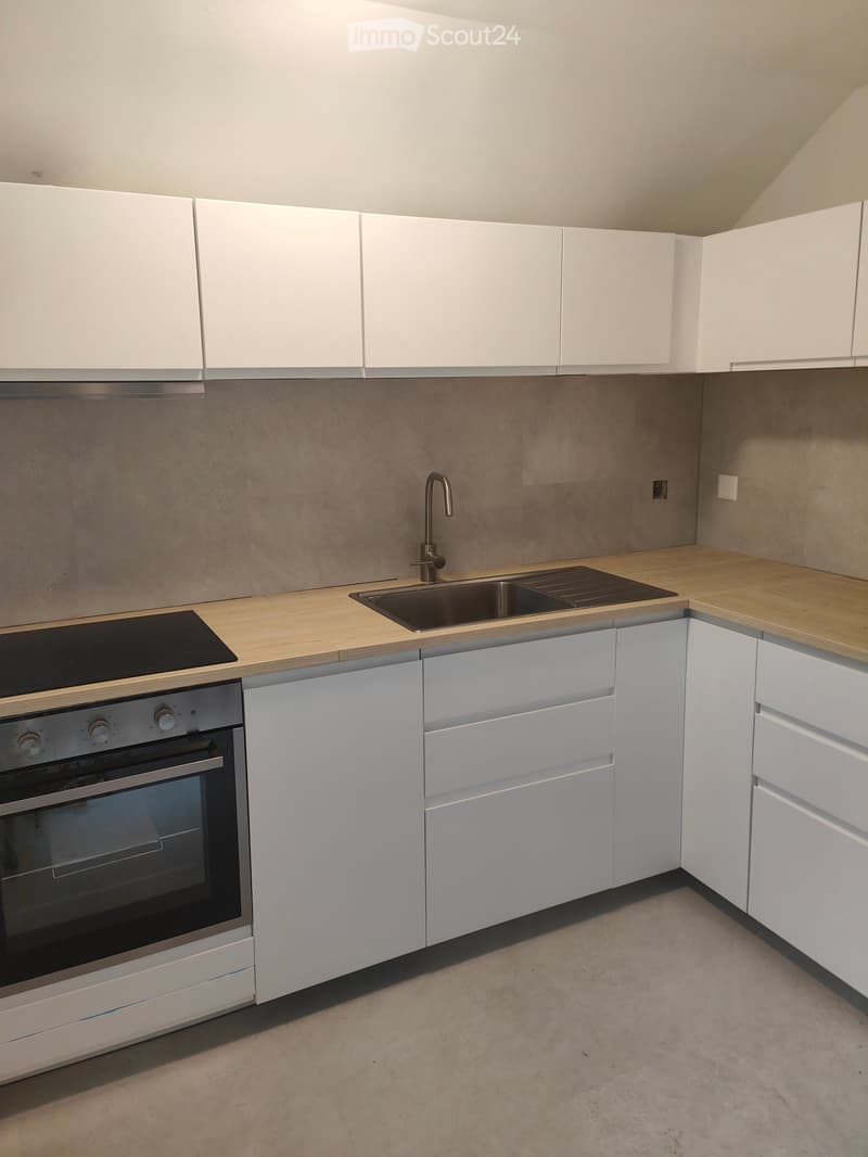 Modern kitchen with white cabinets, wooden countertops, stainless steel sink, and built-in oven.