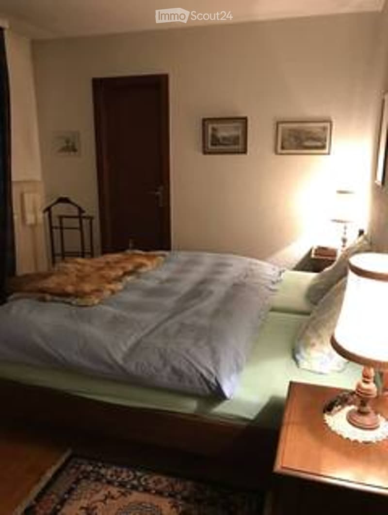 Cozy bedroom with a large bed, nightstand, lamp, and picture frames on the wall.