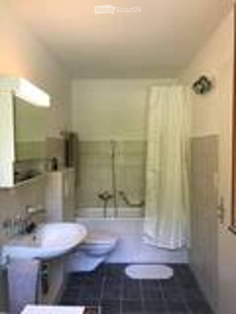Modern bathroom with white tiles, a sink, mirror, toilet, bathtub, and a shower curtain.