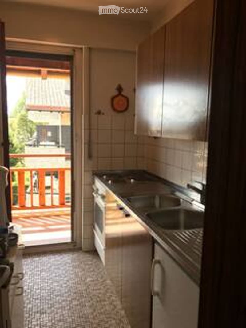 Modern kitchen with white cabinets, stainless steel sink, oven, and a balcony access door.