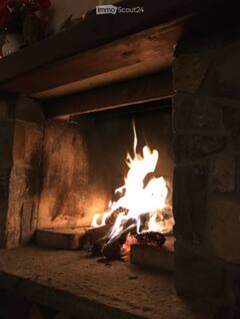 A stone fireplace with a roaring fire, surrounded by brick walls and a wooden mantel.