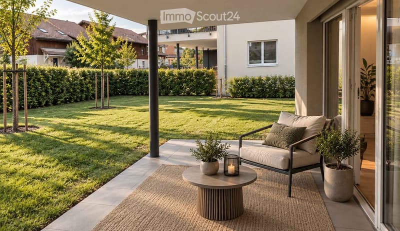 A modern outdoor patio area with a round wooden coffee table, a lounge chair, and potted plants, overlooking a well-maintained lawn and garden.