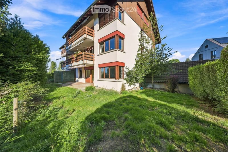 A two-story house with a modern design, featuring a balcony on the upper floor, large windows, and a well-maintained garden.