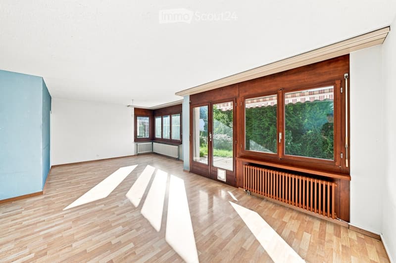 Empty room with wooden flooring, white walls, large windows, and radiators. No furniture or equipment present.