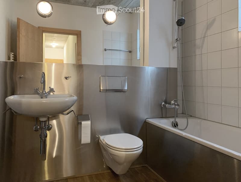 Modern bathroom with a sink, toilet, bathtub, and showerhead. Features a large mirror and sleek metallic finishes.