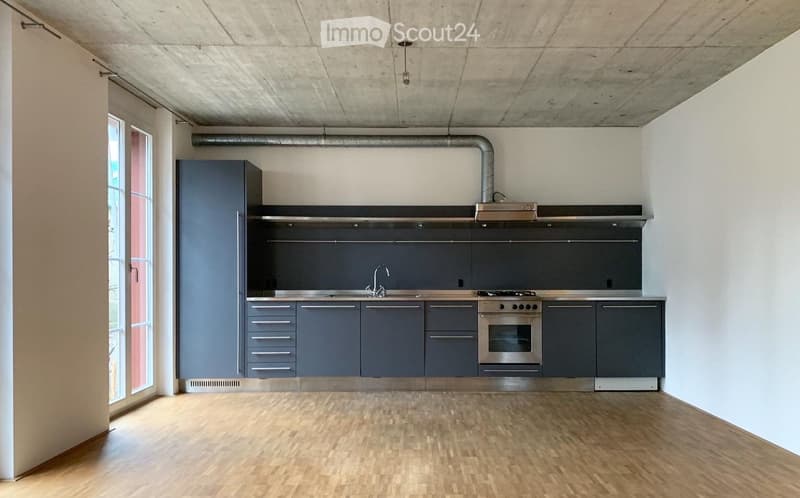 Modern kitchen with grey cabinets, stainless steel appliances, and wooden flooring.