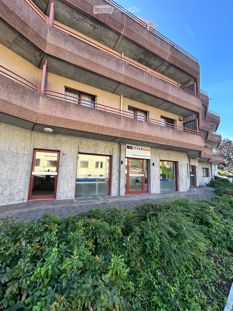 Multi-story building with concrete facade, red-framed windows, and a sign reading "RITTERBAU" above the entrance.