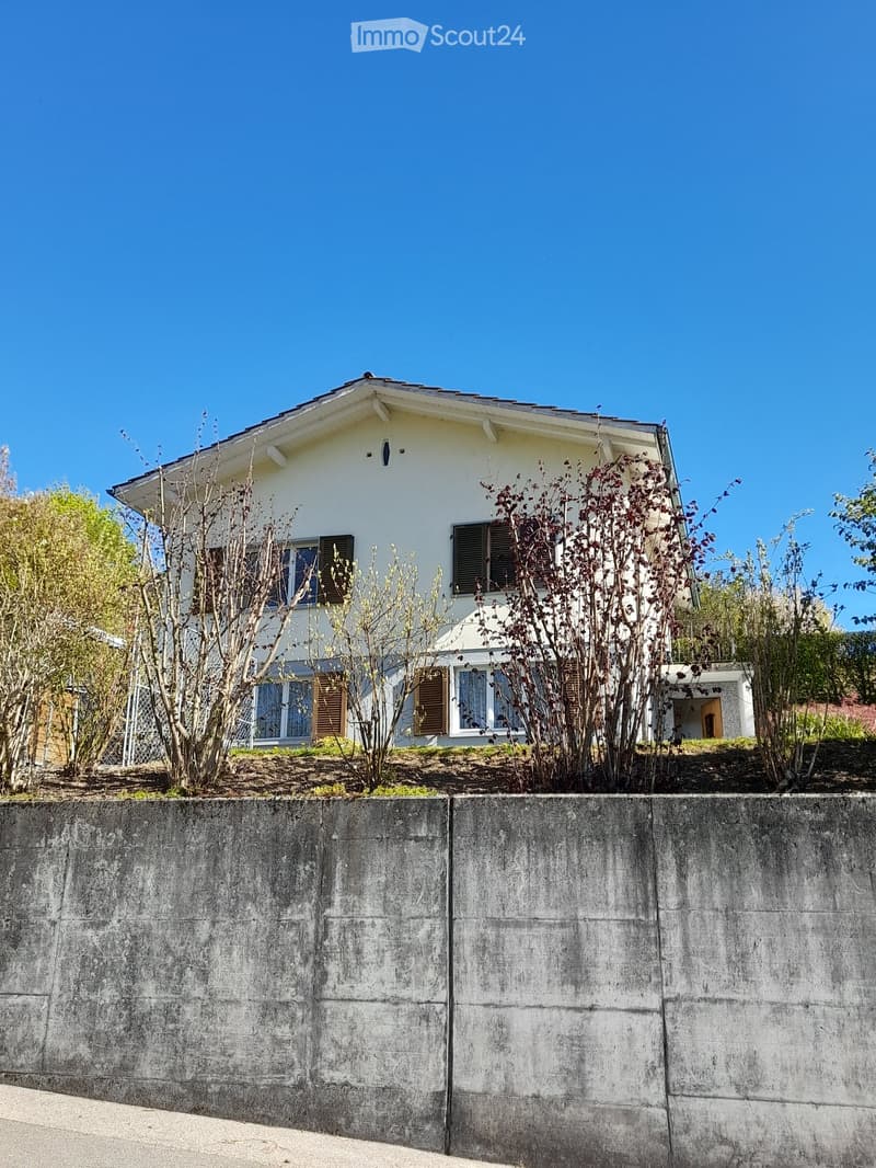 2 story house, white exterior, brown shutters, concrete wall, garden