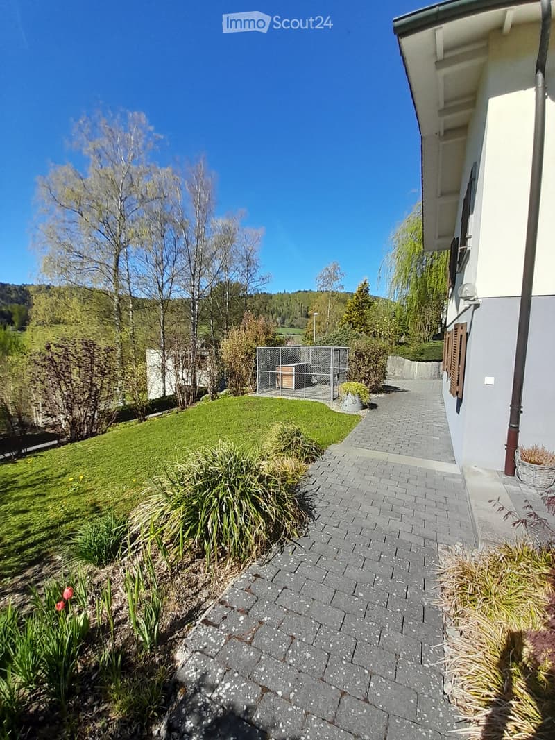 brick pathway, green lawn, shrubs, trees, metal fence, house