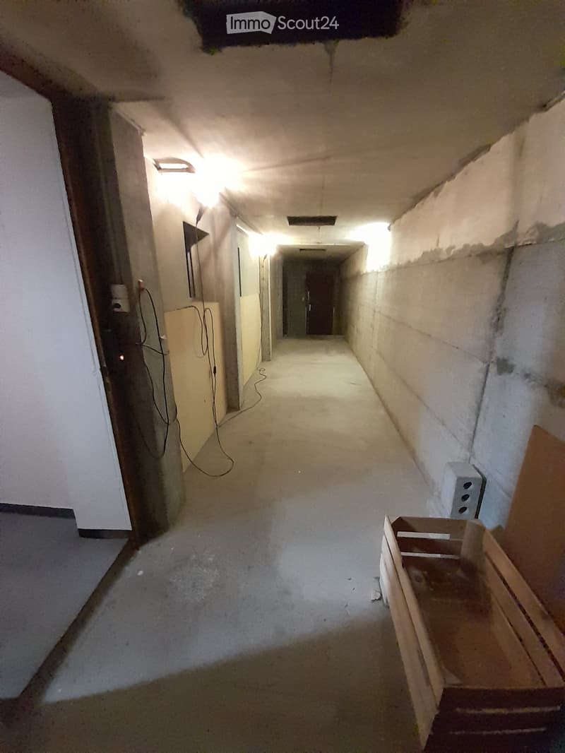 Empty hallway, concrete walls, white ceiling, lights on the ceiling, wooden storage box