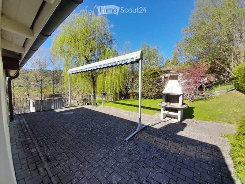 brick paved terrace, awning, barbecue, green grass, trees, mountains in the distance