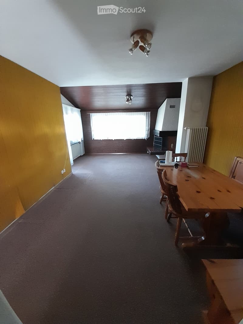 empty room, wooden table, wooden chairs, yellow walls, fireplace, radiator, windows