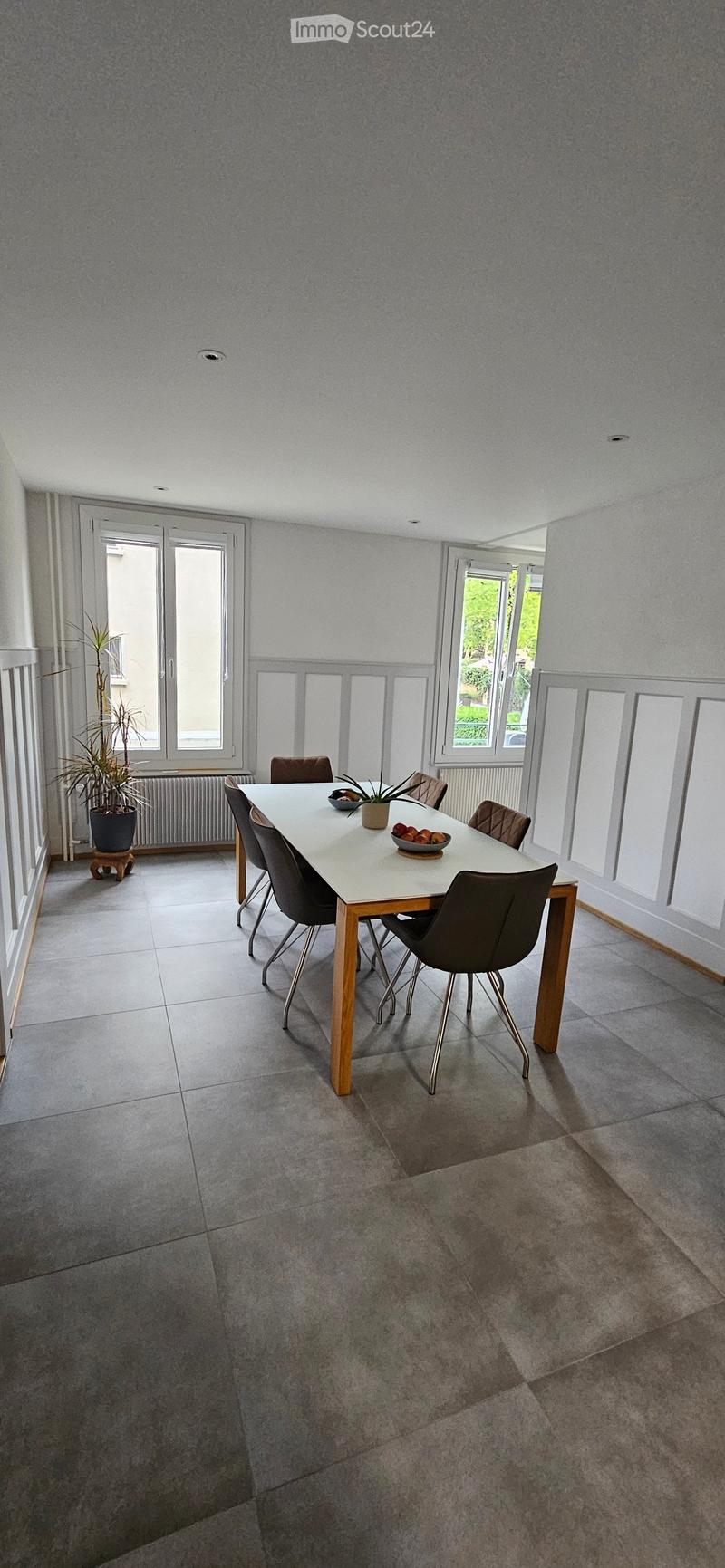 Bright dining room with a white dining table, six chairs, and a potted plant near the window.