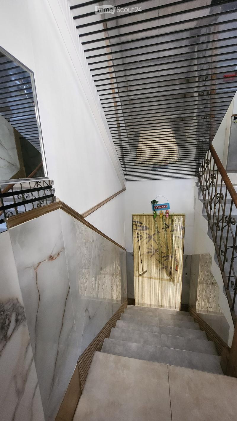 Staircase with marble steps, wooden handrails, and decorative elements including a 'Welcome' sign and a bamboo screen.