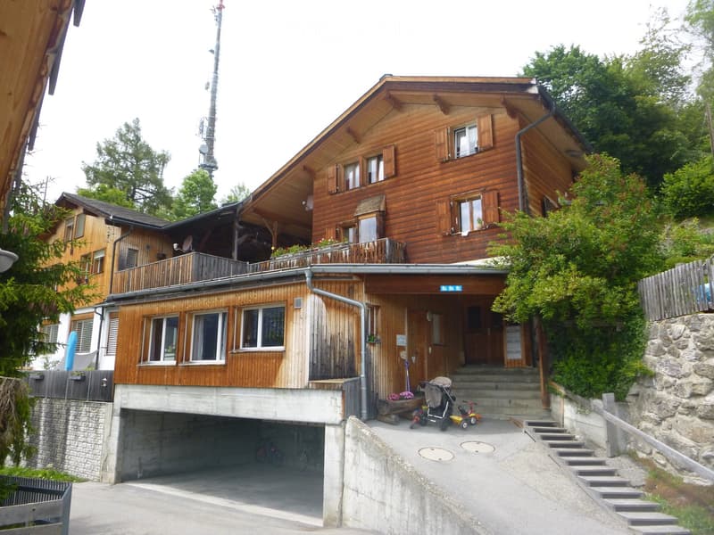 Two-story wooden house with a garage, balcony, and steps leading up to the entrance.